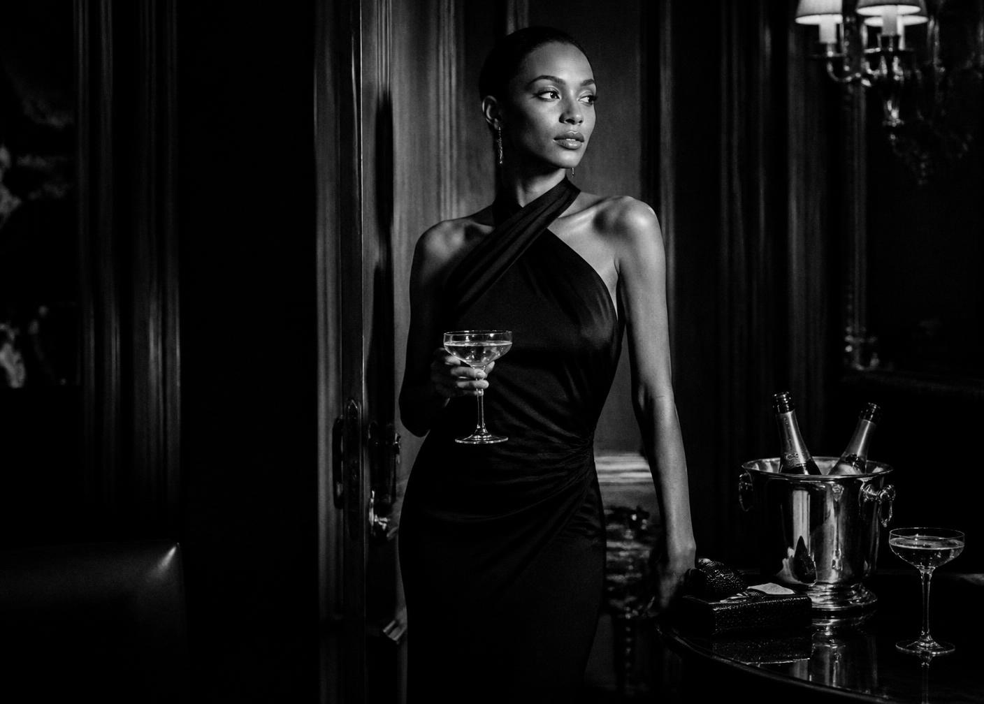 Woman in a black evening gown with champagne in a dark salon